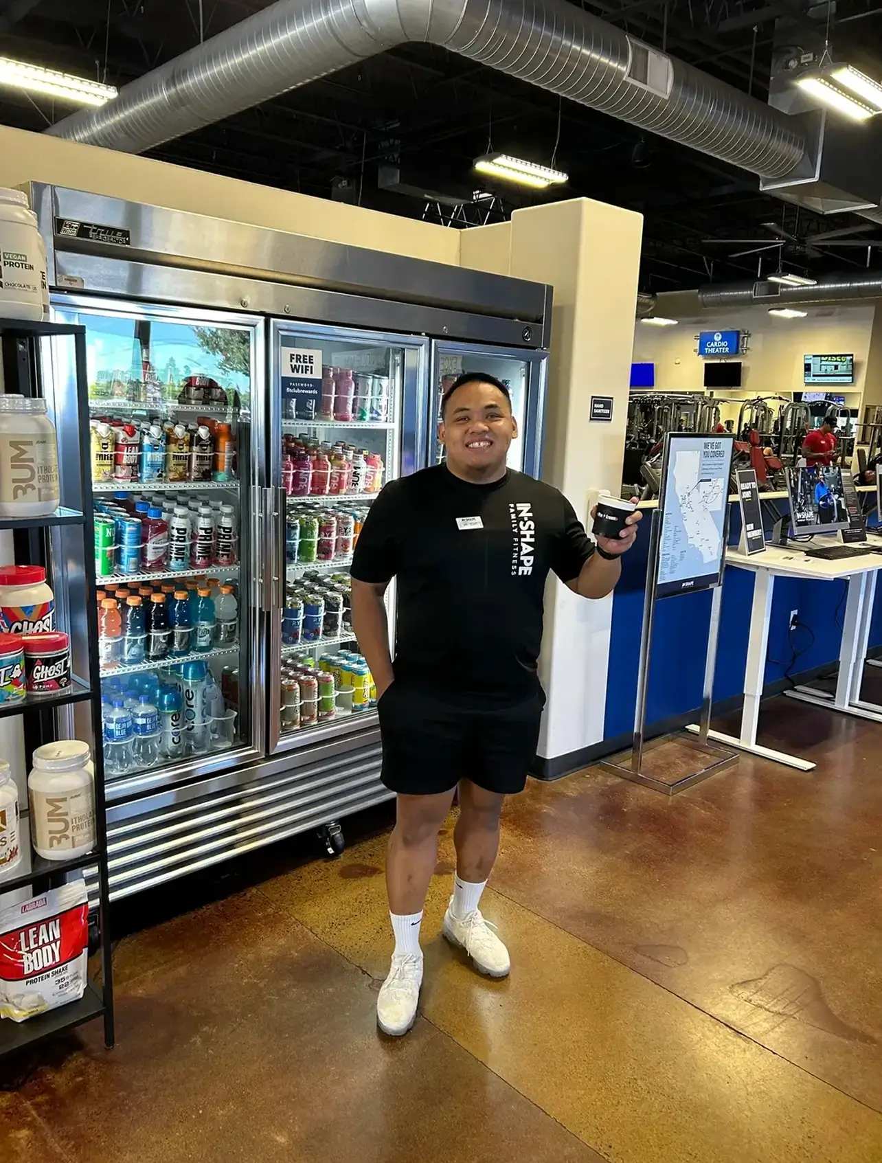 A man in casual attire posing inside a store near refrigerators.