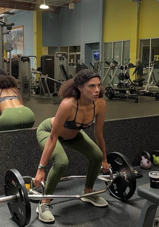 Woman lifting weights in a gym, focused on her workout.